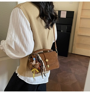 Brown faux leather crossbody bag with teddy pendant and striped scarf on model