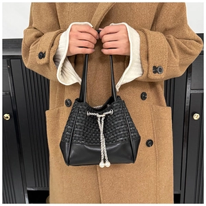 Detail of black woven PU leather bucket bag with silver chain and pearl drawstrings