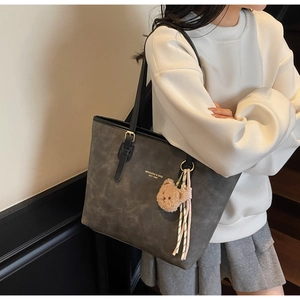Detail of dark grey tote bag with faux leather straps and cute plush bear accessory