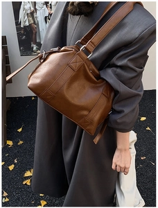 Detailed view of brown faux leather Boston bag with X-stitch design and silver metal rings