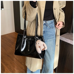Détail d'un sac cabas en cuir verni noir avec un charmant pendentif lapin en peluche