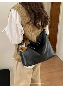 Vue latérale d'un grand sac fourre-tout en cuir noir avec pendentif étoile et ours