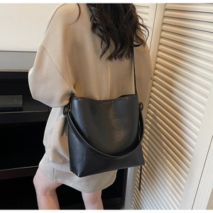 Detail of black leather bucket bag with white contrast stitching and dual strap options