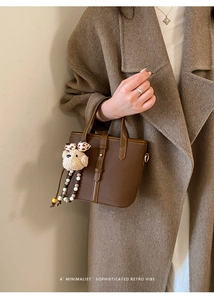 Detail showing retro dark brown lychee texture bucket bag with bear charm and buckle