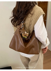 Détail d'un sac hobo marron avec breloques étoile et ours dans un décor de style de vie