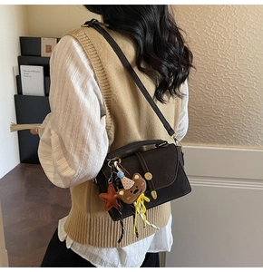 Detail of dark brown retro leather handbag with golden round clasp and decorative charms