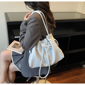 Close-up of light blue drawstring bucket bag with star pendant and textured leather finish