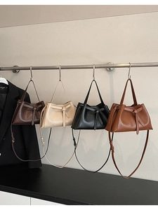 Row of versatile leather tote bags in four earth tones hanging on a metal rack