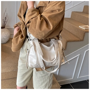 Detail of off-white lychee pattern tote bag with side ties on a lifestyle model