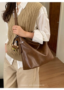 Détail d'un sac cabas en cuir marron avec breloque ours et accessoire foulard rayé