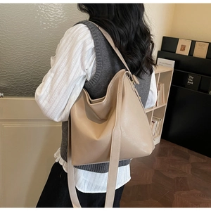 Close-up of beige leather tote bag shoulder strap and textured material on a model