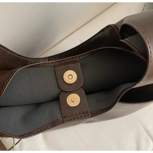 Détail des doubles fermoirs magnétiques et doublure en tissu gris sur ce sac en cuir brun