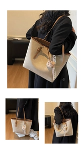 Detail of a beige tote bag with brown trim, teddy bear charm and woven tassel detail