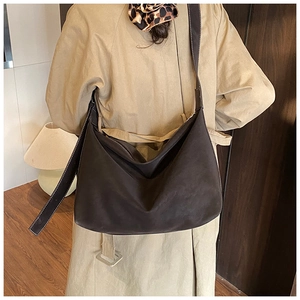 Detail view of suede tote bag featuring white stitching on a shoulder strap for commuting