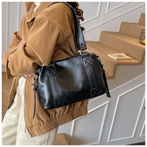 Detail of black leather tote bag with vintage texture and reinforced X-shaped stitching
