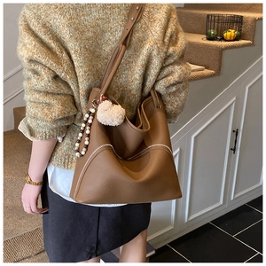 Detailed view of brown lychee-grain bucket bag with white stitching and bead charm