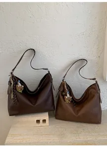 Détail de grands cabas marron en cuir mat avec d'adorables pendentifs d'ours en peluche