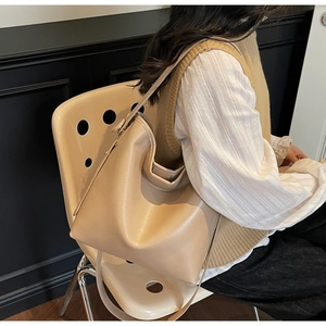 Close-up of a beige faux leather bucket bag with adjustable shoulder strap and metal hardware