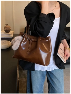 Détail du sac cabas en cuir ciré brillant marron foncé avec un pendentif lapin en peluche