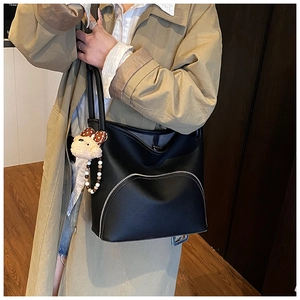 Detail of black pebbled leather tote with silver zipper pocket and cute bear charm