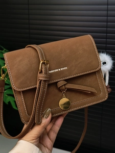 Brown vintage leather crossbody bag with white stitching and plush doll charm