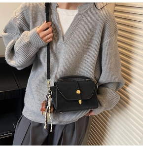 Detail of black matte leather handbag with gold twist lock and woven star charm