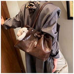 Détail du cabas en cuir marron foncé avec un joli pendentif animal en peluche sur l'anse