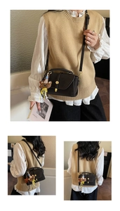 Detail of dark brown vintage crossbody bag with a cute bear plush charm on the flap