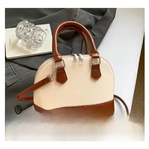 Detail of a two-tone shell handbag with cream and brown leather finish and silver hardware