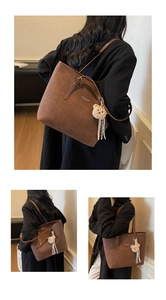 Detail showing the brown frosted leather texture and cute plush bear charm on the tote bag