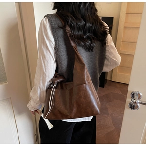 Détail du sac hobo vintage en cuir synthétique marron foncé avec cordon et large bandoulière