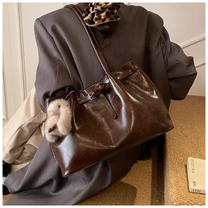 Détail du sac cabas en cuir marron foncé avec sangle vintage et peluche lapin