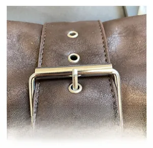 Detail of vintage dark brown leather bag with metallic silver buckle and eyelets