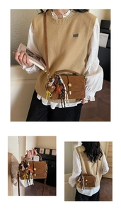 Detail view of brown vintage satchel with teddy bear charm and plaid ribbon accents