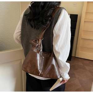 Détail du sac à bandoulière vintage marron foncé avec un pendentif Maven & Chic chic