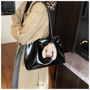 Détail d'un cabas en cuir noir brillant avec pendentif lapin en peluche et boucle déco