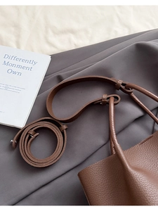Detail of lychee pattern leather bucket bag with top handle and rolled crossbody strap
