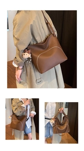 Detail of brown lychee grain leather tote bag with curved metal zipper and bear pendant