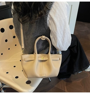 Detail of cream-white lychee texture tote bag featuring gold buckle and branding