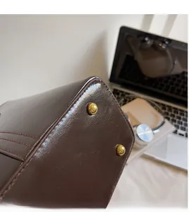 Close-up of dark brown leather tote bottom with protective golden metal feet studs