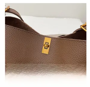 Detail of premium golden metal twist lock on brown lychee texture leather handbag