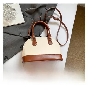 Detail of cream and tan contrast shell bag with double handles and metal base feet