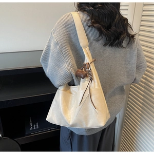 Détail du sac hobo en cuir crème avec poche latérale et élégante mini breloque