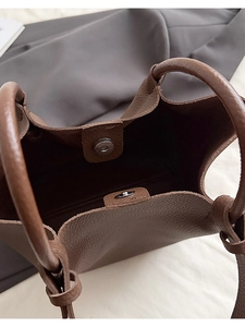 Detail of dark brown pebble leather bag featuring round magnetic closure and handles