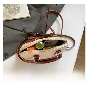 Interior view showing the capacity of a beige shell bag with a phone and makeup items