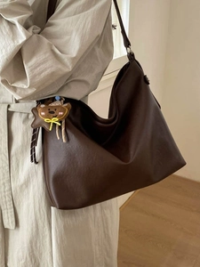 Sac cabas en cuir mat marron avec charm ours, porté par un mannequin pour un look urbain