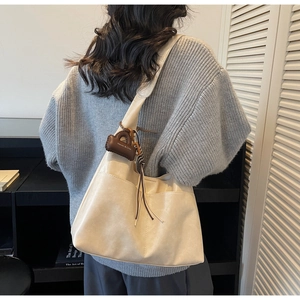 Vue détaillée du sac cabas blanc crème avec coutures verticales et pendentif mini pochette