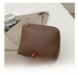 Close-up of hand holding a vintage dark brown lychee leather handbag with gold zipper