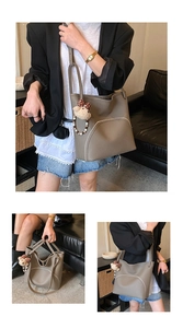 Detail view of taupe vintage tote bag with decorative side zipper and plush bear charm