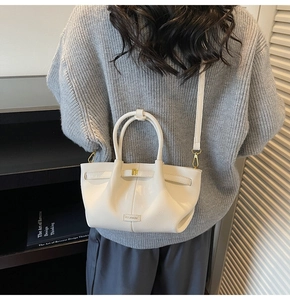 Rear view of model wearing a beige litchi leather tote with textured fold details